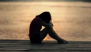 Chica adolescente con los brazos contra las rodillas, en posición recogida que sugiere vulnerabilidad emocional