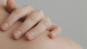 Persona tocándose el hombro con la mano, gesto de autocuidado y atención personal