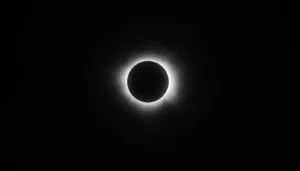 Imagen en blanco y negro de un eclipse, con el contorno luminoso del sol oculto por la luna