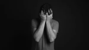 Hombre tapándose la cara en señal de estrés, en blanco y negro